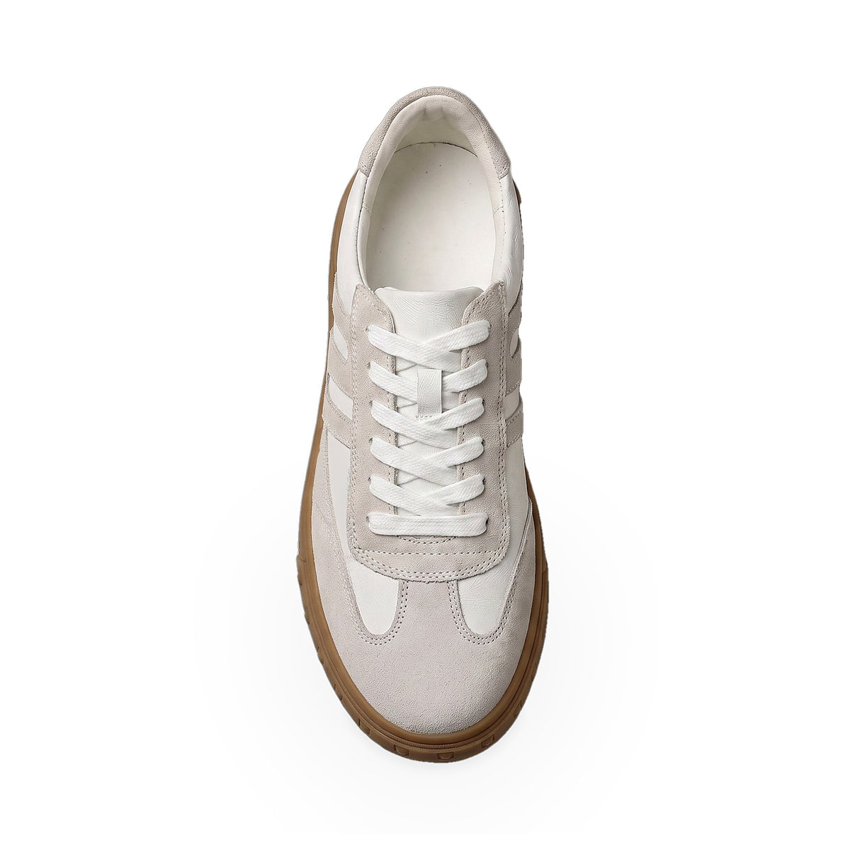 A top-down view of a low-top sneaker in light beige suede and white leather, featuring white laces and a brown gum sole, set against a plain white background.